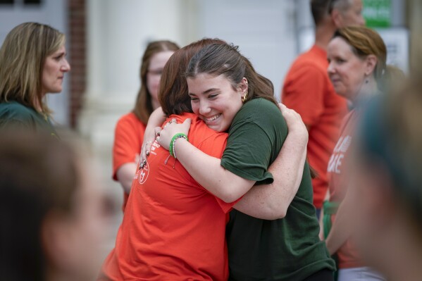 Emma Ehrens, a survivor of the 2012 Sandy Hook Elementary School shooting, hugs a family friend during a rally against gun violence on Friday, June 7, 2024 in Newtown, Conn. (AP Photo/Bryan Woolston)