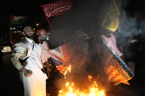 FILE - Iranian demonstrators burn representations of British and U.S. flags during a protest against the U.S. and British military strike against Iranian-backed Houthis in Yemen, in front of the British Embassy in Tehran, Iran, Jan. 12, 2024. The next president could be "forced to either sell Iran to Trump or spark a dangerous tension in the country” if economic problems aren't solved, warned Mohammad Bagher Qalibaf, Iran’s parliament speaker and a candidate in the election to be held on Friday, June 28, 2024. (AP Photo/Vahid Salemi, File)