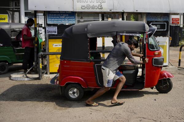 A man pushes his autorickshaw to a fuel station in Colombo, Sri Lanka, Wednesday, July 27, 2022. Sri Lanka's economic crisis has left the nation's 22 million people struggling with shortages of essentials, including medicine, fuel and food. (AP Photo/Eranga Jayawardena)