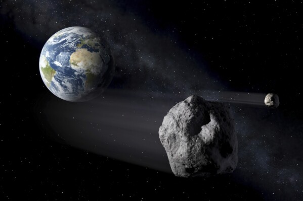 In this artistic rendering, two asteroids fly past Earth. An asteroid will whiz harmlessly past Earth Saturday June 29, 2024. With the right equipment and timing, you just might spot it. Called 2024 MK, the space rock will make its closest approach to Earth at 9:46 AM EST (13:46 GMT) passing by at about three-quarters the distance from Earth to the moon. It was first spotted two weeks ago by South African astronomers and is about 393 feet to 853 feet (120 to 260 meters) wide. (ESA via AP)