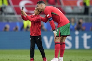 A young pitch invader takes a selfie with Portugal's Cristiano Ronaldo during a Group F match between Turkey and Portugal at the Euro 2024 soccer tournament in Dortmund, Germany, Saturday, June 22, 2024. (AP Photo/Themba Hadebe)