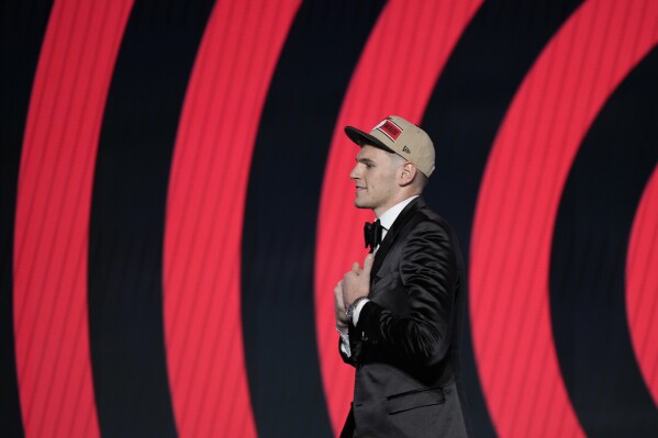 Donovan Clingan walks across the stage after being selected by the Portland Trail Blazers as the seventh pick during the first round of the NBA basketball draft, Wednesday, June 26, 2024, in New York. (AP Photo/Julia Nikhinson)
