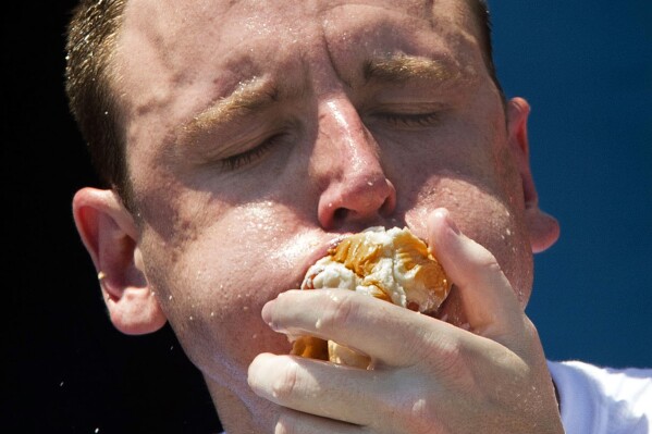 FILE - Five-time reigning champion Joey Chestnut competes in the Nathan's Famous Hot Dog Eating World Championship, July 4, 2012, in the Coney Island section of the Brooklyn borough of New York. The annual Nathan’s Famous Fourth of July hot dog eating contest will see a slate of competitive eaters wolf down as many franks as they can in New York City on Thursday, July 4, 2024 — but this year, the event’s biggest star, Chestnut, will be chowing down 1,900 miles (3,000 km) away. (AP Photo/John Minchillo, File)