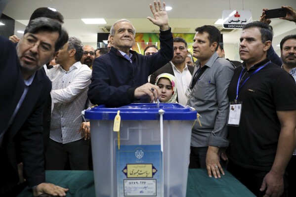 In this photo provided by Iranian Students' News Agency, ISNA, reformist candidate for the Iranian presidential election Masoud Pezeshkian casts his ballot as he waves to media in a polling station, in Tehran, Iran, Friday, June 28, 2024. Iranians are voting in a snap election to replace the late hard-line President Ebrahim Raisi. (Majid Khahi, ISNA via AP)