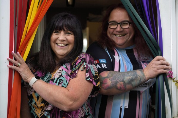 Avril Clark, left, and Lucy pose for a photograph during an interview at their house in London, Tuesday, June 11, 2024. Avril Clark operates the group Distinction Support, a U.K.-based global online network that helps people whose partner went through or is undergoing a gender transition. Her spouse, a British soccer referee at the time, came out publicly as transgender in 2018, changed her name to Lucy and brought the couple much attention. Avril Clark says that until then, they kept their arrangement private and "lived a double life" for 15 years. (AP Photo/Kin Cheung)