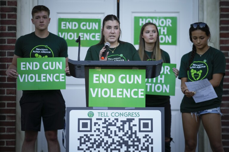 Emma Ehrens, center, a survivor of the 2012 Sandy Hook Elementary School shooting speaks as she stands with other survivors during a rally against gun violence on Friday, June 7, 2024 in Newtown, Conn. (AP Photo/Bryan Woolston)