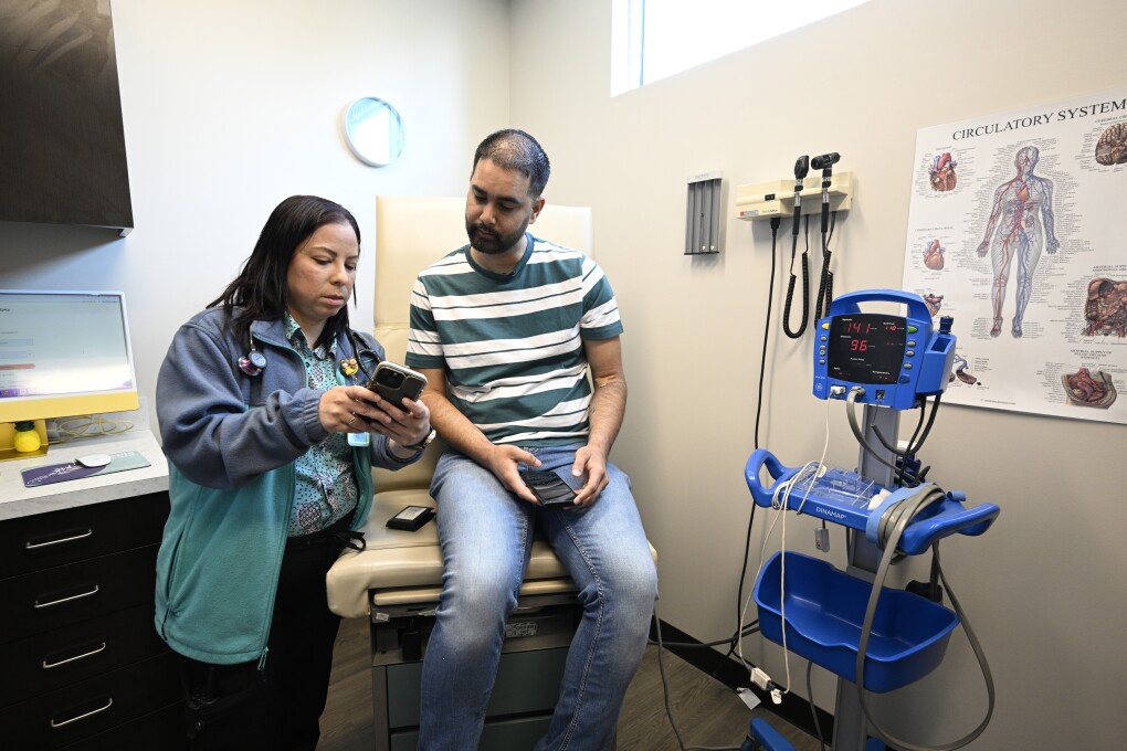 Nurse practitioner Eliza Otero, left, talks with Fernando Hermida during his visit at Pineapple Healthcare in Orlando, Fla., on May 28, 2024. The clinic serves an LGBTQ+ population, especially Latinos living with HIV. (AP Photo/Phelan M. Ebenhack)