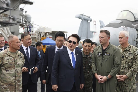 FILE - South Korean President Yoon Suk Yeol, center, boards the USS Theodore Roosevelt aircraft carrier at the South Korean naval base in Busan, South Korea, Tuesday, June 25, 2024. The newly-inaugurated Freedom Edge exercise is wrapping up in the East China Sea, having brought together Japanese, South Korean and American naval assets for multi-domain maneuvers for the first time. (South Korean Presidential Office/Yonhap via AP, File)