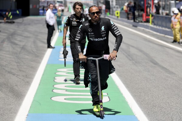 Mercedes driver Lewis Hamilton of Britain rides a scooter outside his box ahead of the Formula 1 Spanish Grand Prix race at the Barcelona Catalunya racetrack in Montmelo, near Barcelona, Spain, Sunday, June 23, 2024. (Thomas Coex, Pool Photo via AP)