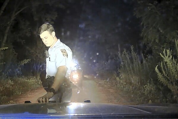 This image from a dashboard-mounted video camera on a Georgia State Patrol cruiser shows Trooper 1st Class Jake Thompson at the scene of an Aug. 7, 2020, shooting in which the trooper killed motorist Julian Lewis in Screven County, Ga. Thompson knocked Lewis' car into a ditch and shot him after trying to pull over the 60-year-old Black man for a broken taillight. Thompson was fired and charged with murder, but walked free after a grand jury declined to indict him. The newly released video raises new questions about the shooting. (Georgia Department of Public Safety/Ebony Reed, Louise Story via AP)