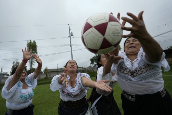 Indigenous women fight for the ball during a "handball with anaco" match in the Indigenous community of Turucu, Ecuador, Friday, June 14, 2024. One year ago, a group of women decided to create a new version of soccer: handball with anaco, an ancient skirt worn by Indigenous women. (AP Photo/Dolores Ochoa)