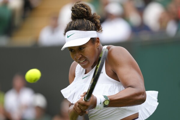Naomi Osaka of Japan plays a backhand return to Diane Parry of France during their first round match of the Wimbledon tennis championships in London, Monday, July 1, 2024. (AP Photo/Kirsty Wigglesworth)
