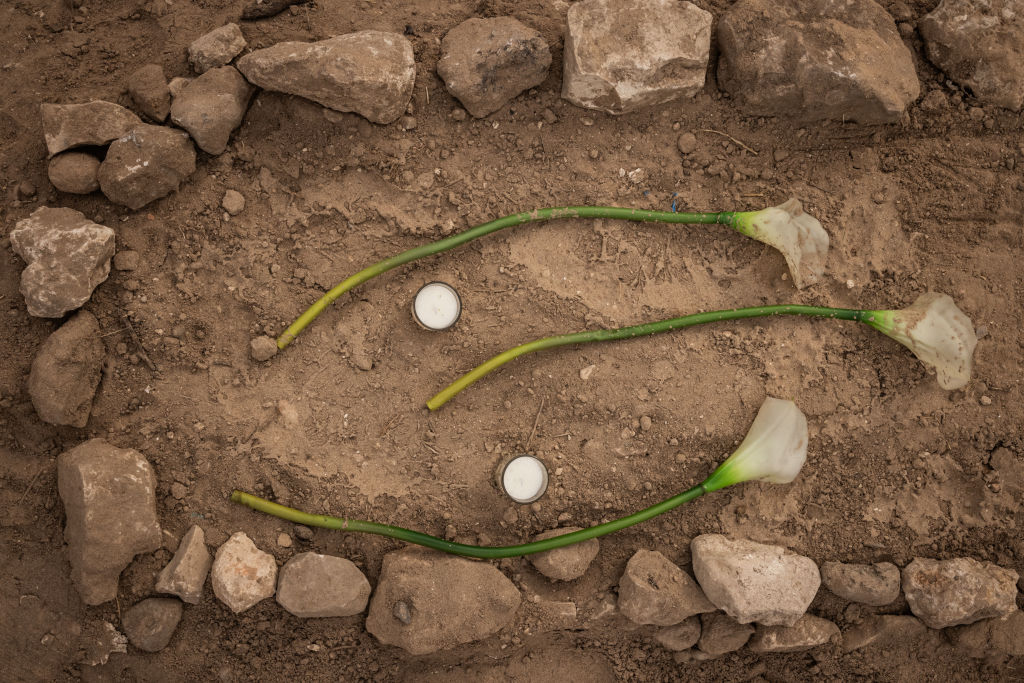 Flowers lie on a temporary grave as graves of civilians and fighters were exhumed for relocation on December 4, 2024 in Tyre, Lebanon. Israel and Hezbollah had agreed to a truce in late November, aiming to end 13 months of hostilities. It has proven fragile in the days since, with each side accusing the other of violations.