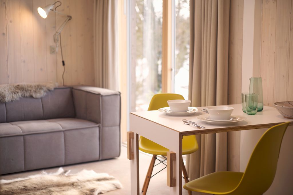 Modern interior of The Woodshed, with table for two with yellow chairs and grey sofa next to the French doors