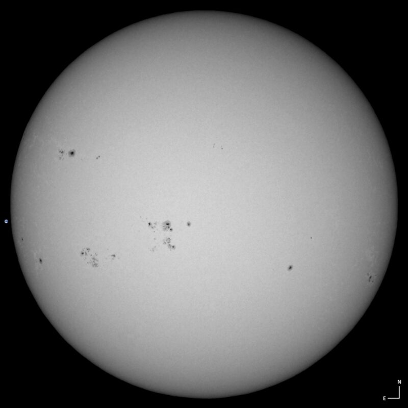 The sun, seen as a large white sphere with small dark spots.