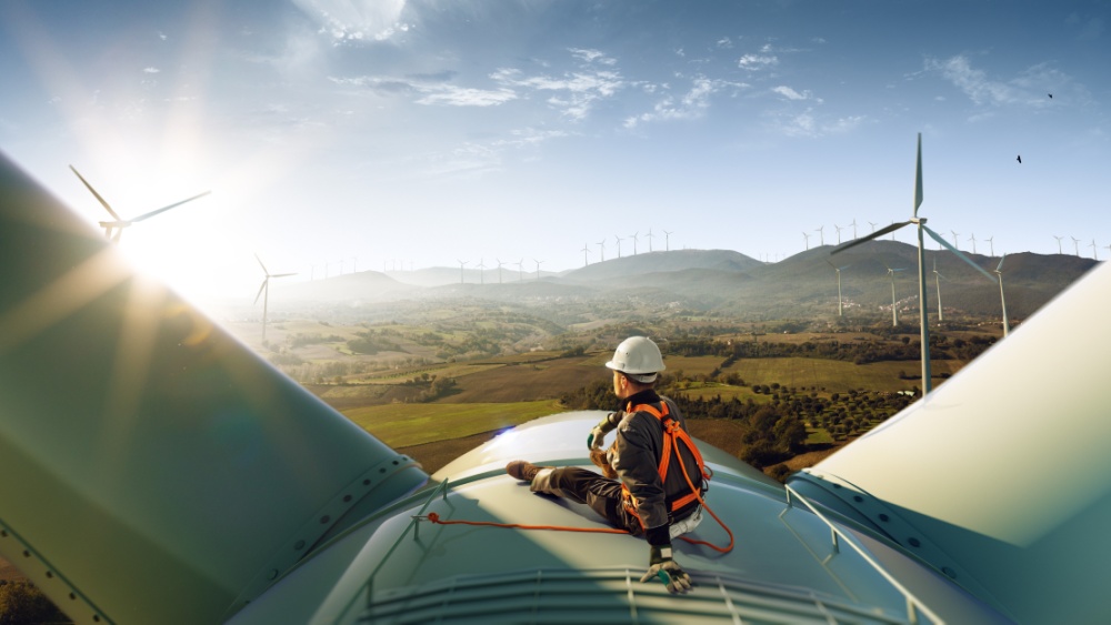 A person working on a wind turbine wearing protective helmet.