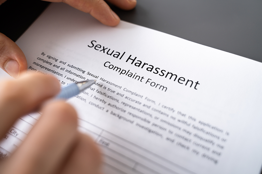 Close-up of a person's hand filling sexual harassment complaint form