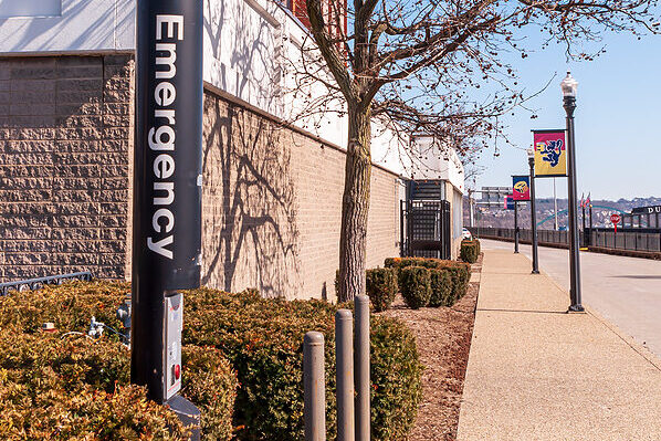 A black emergency phone pole standing on a college campus's grounds