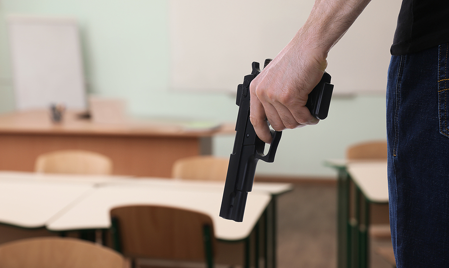 A person's hand holding a gun in a school environment