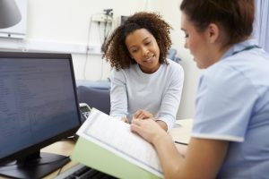 A general practice nurse sits with smiling patient at a desk