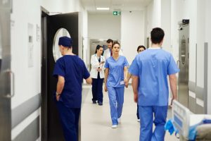 Image shows a mixture of doctors and nurses walking up and down a hospital corridor