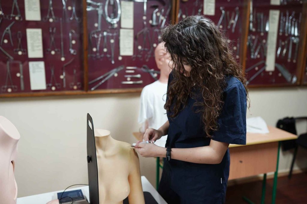 Nurse undertaking simulated practice learning. She is injecting into a manakin in a classroom.