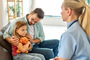 Stock image of nurse visiting a father and child.