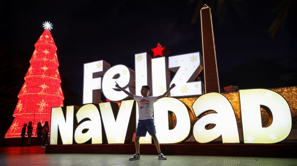 A child plays in front of a Merry Christmas sign as part of the Christmas celebrations in Venezuela