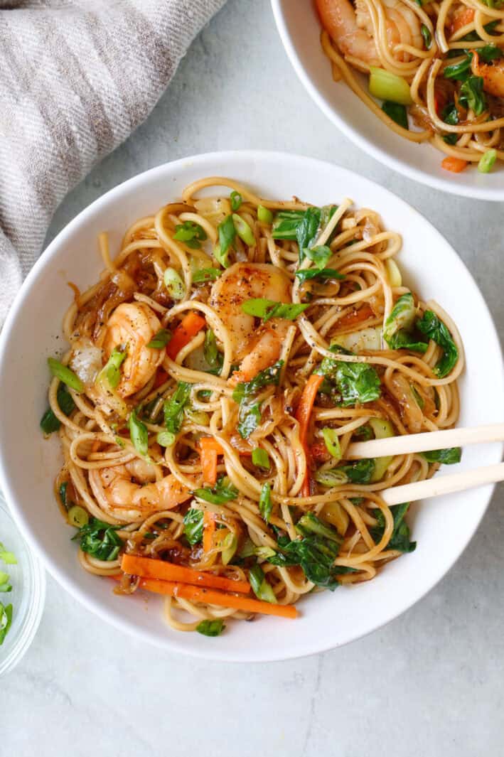 Serving of easy shrimp lo mein recipe in a bowl with tongs.