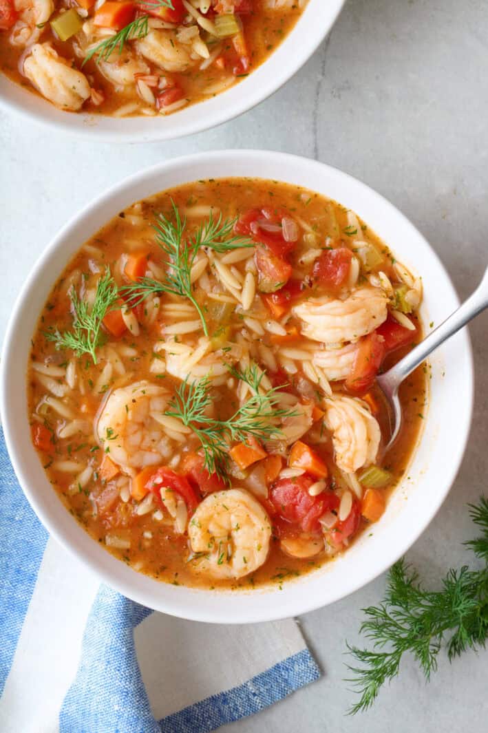 Bowl of shrimp orzo soup garnished with fresh dill.