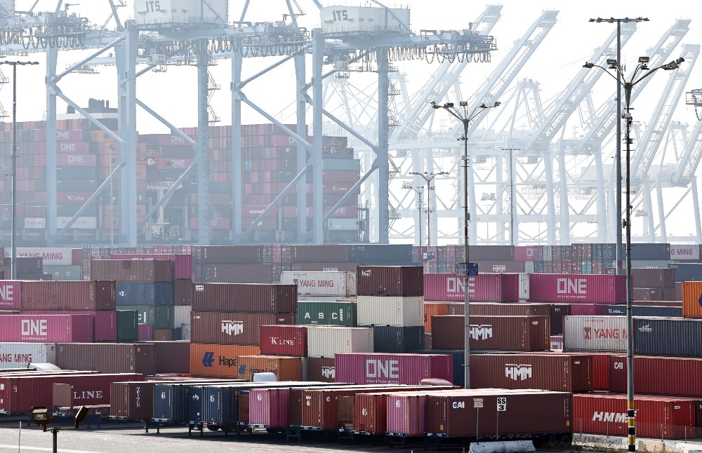 Shipping containers are stacked beneath shipping cranes at the Port of Long Beach on Dec. 4, 2024.