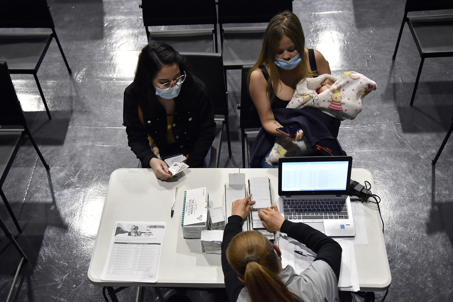 Two Venezuelan migrants, one holding a baby, wait to receive their temporary permission to live and work in Colombia.