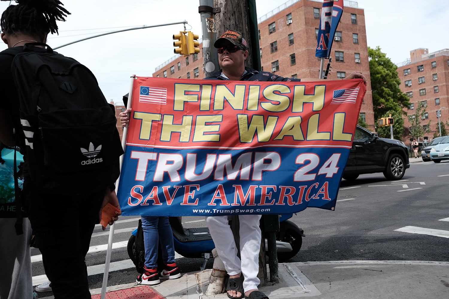 A supporter of Donald Trump holds a sign that reads "Finish the wall. Trump 24. Save America."