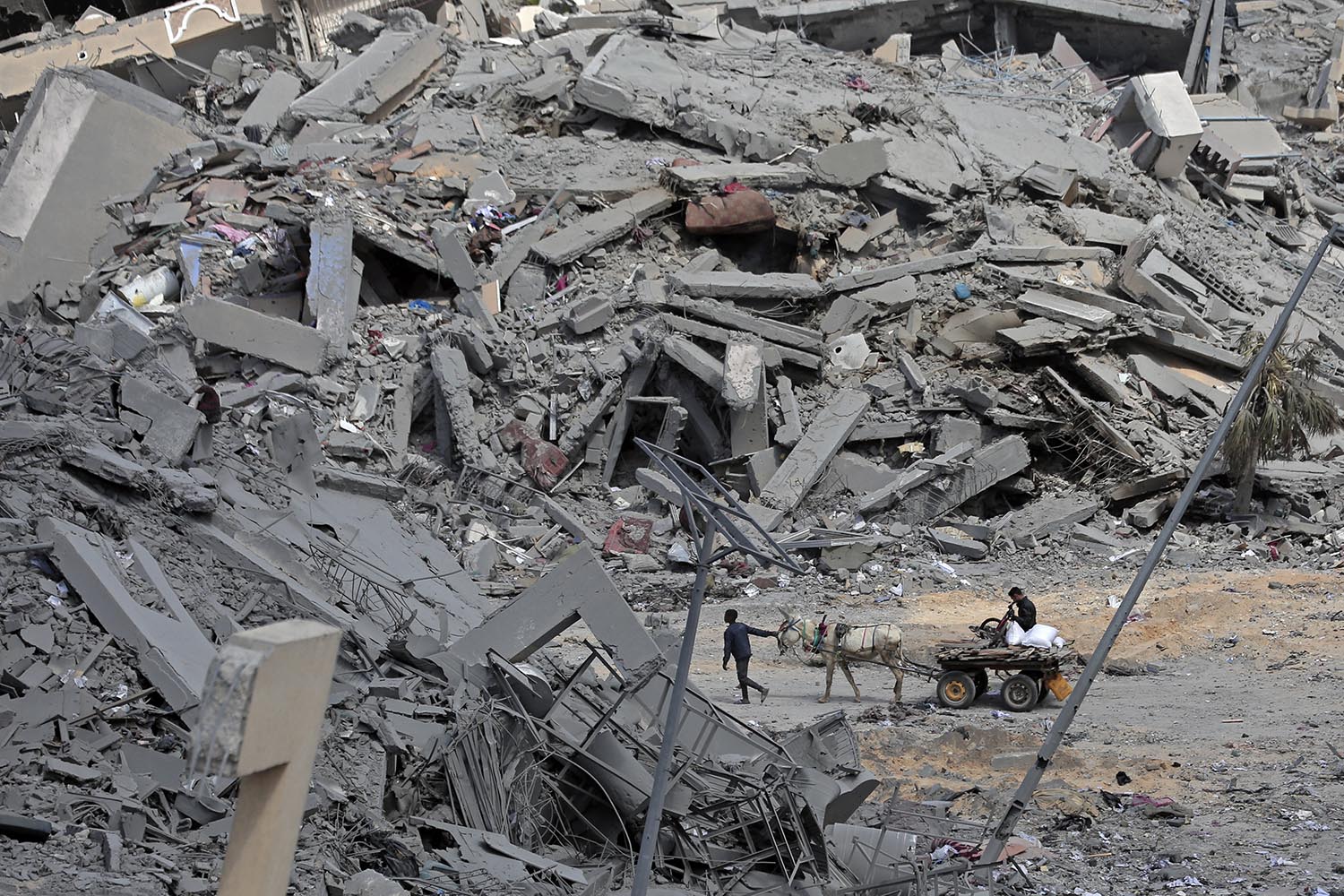 A high-angle view shows giant piles of rubble with two people. One of them is sitting on a horse-drawn cart while the other person.