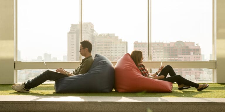 Two people sitting in bean bag chairs, facing away from each other