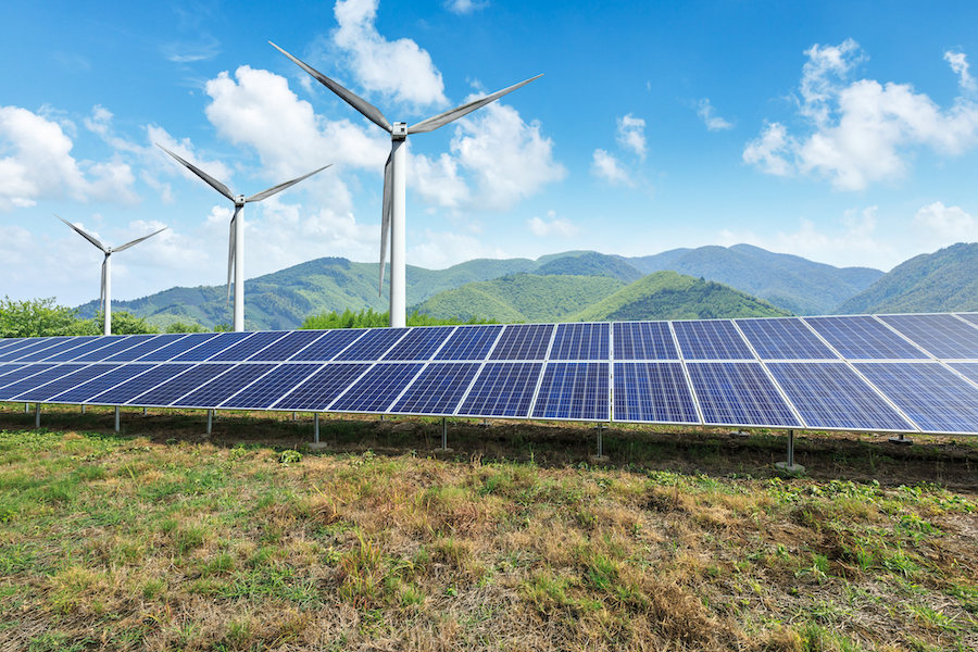 solar panels with wind turbines behind them