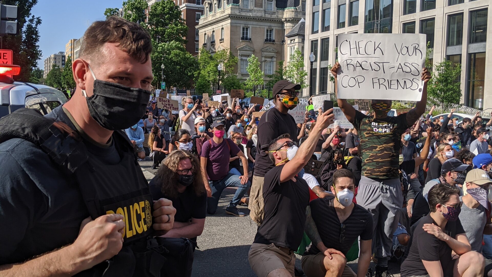 A protester holds a sign saying “check your racist-ass cop friends” near