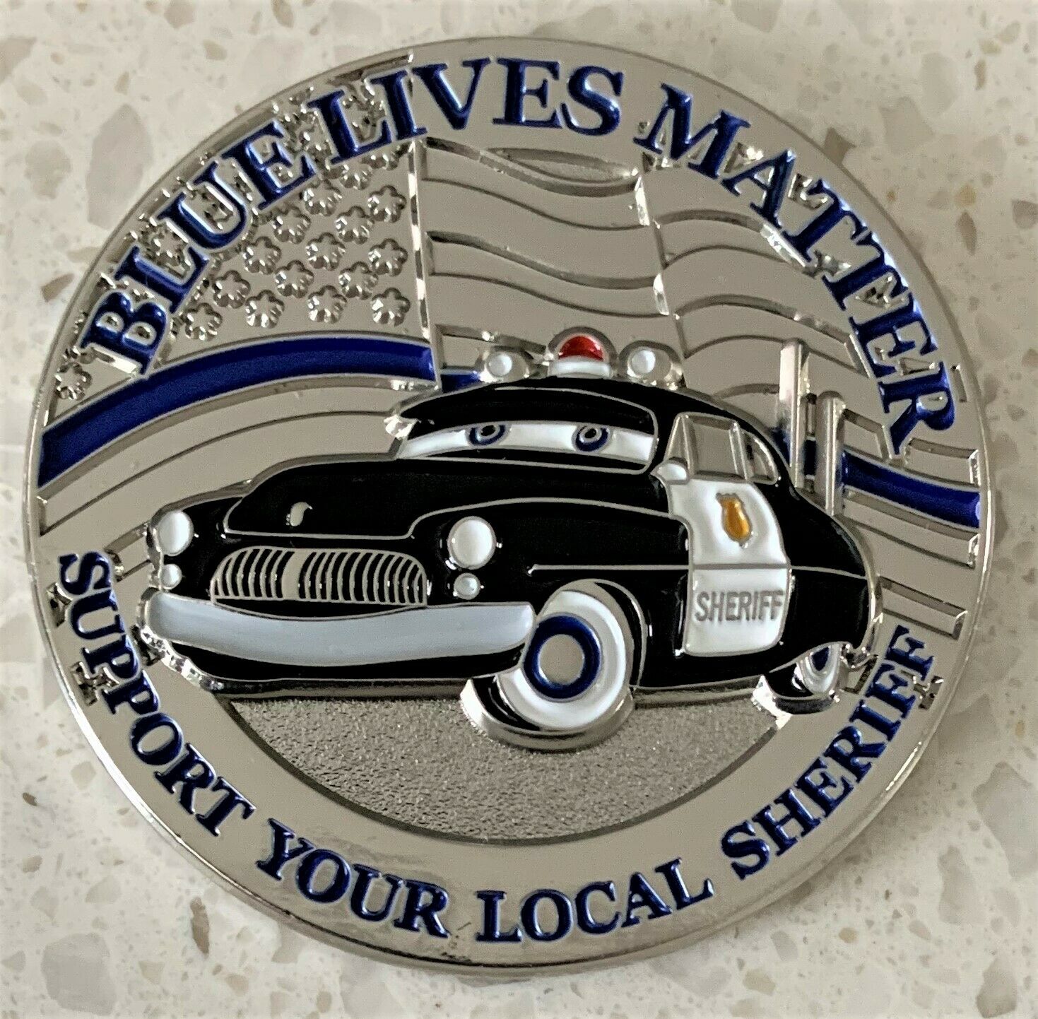 A blue lives matter challenge coin featuring an anthropomorphic police cruiser meant to resemble a character from the Pixar film Cars.