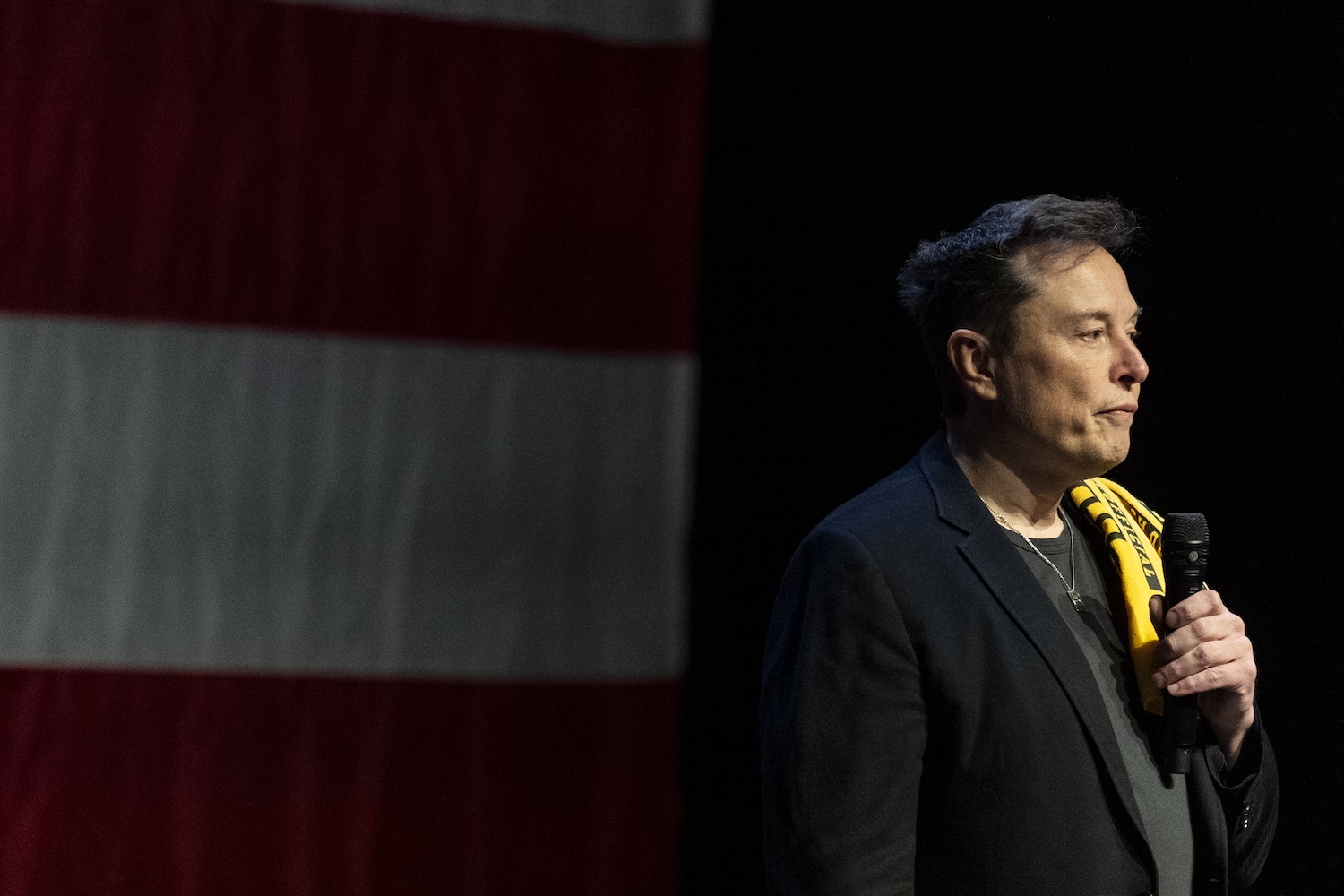 Elon Musk at a Trump rally in Pennsyvlania, holding a shirt over his shoulder.