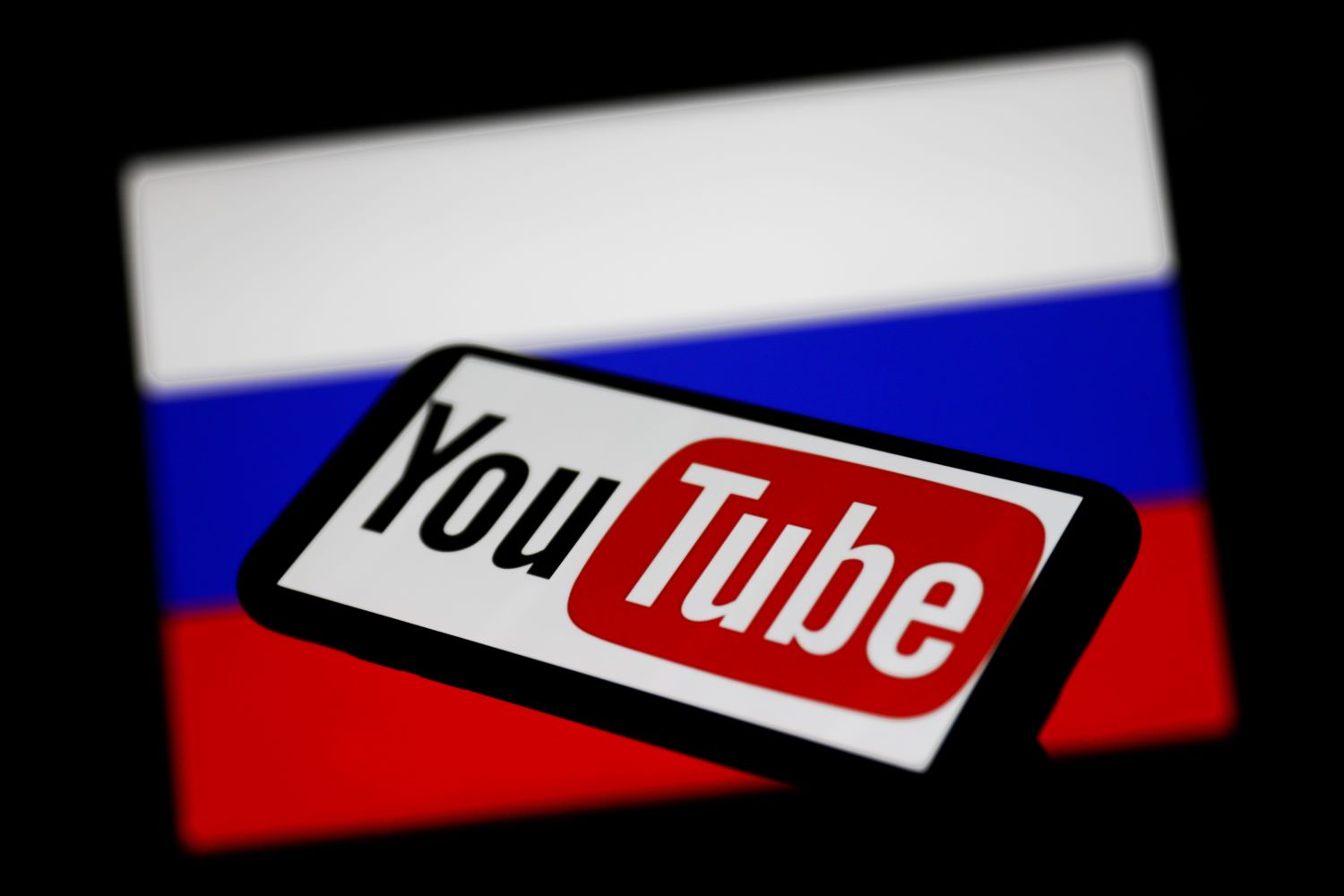 A phone displaying the YouTube logo against a Russian flag background