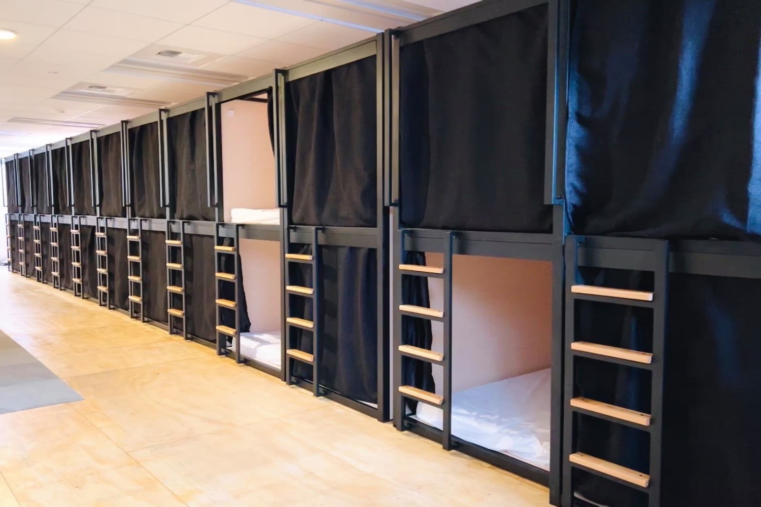 Picture of a row of double-stacked bunkbed "pods" with privacy curtains.