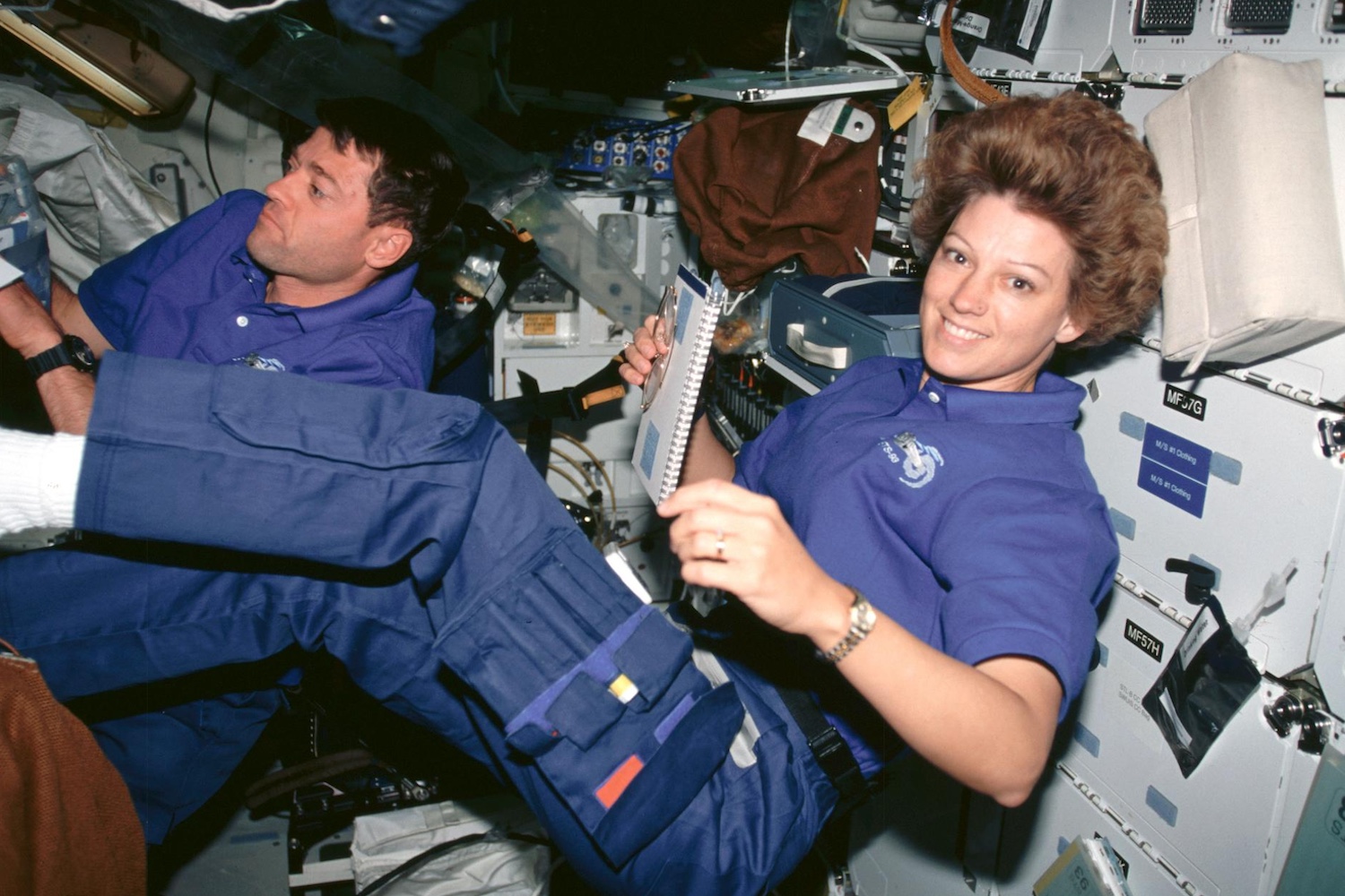 Astronauts Eileen M. Collins, mission commander; and Jeffrey S. Ashby, pilot, peruse checklists on Columbia's middeck.