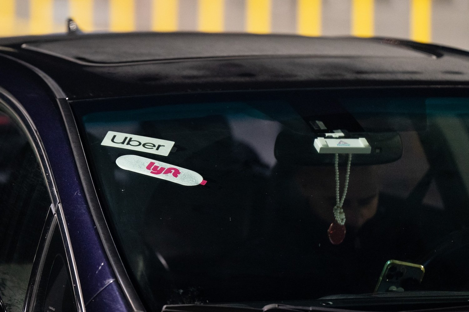 Uber and Lyft logos displayed in a car's windshield.