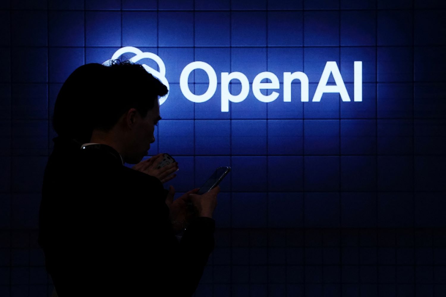 The OpenAI logo with a silhouetted figure in the foreground.