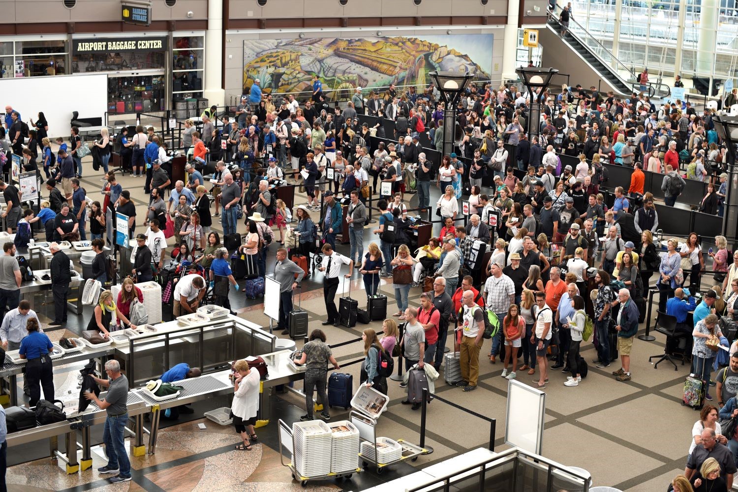 A large crowd of travelers waits to pass through security at an airport.