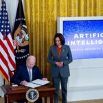 Kamala Harris stands over Joe Biden as he signs the 2023 AI executive order.