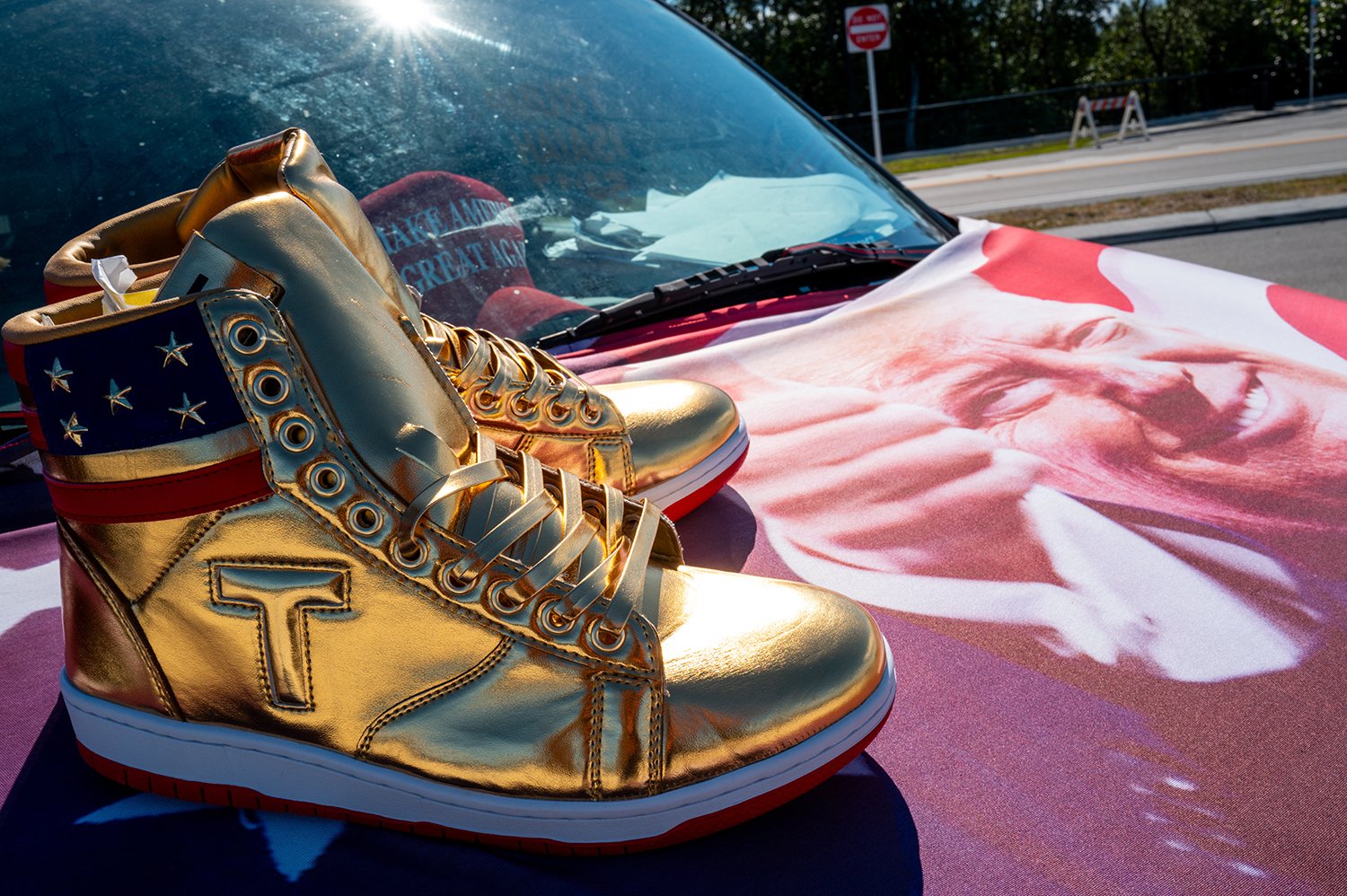 Image of Trump branded shoes on the hood of a car.