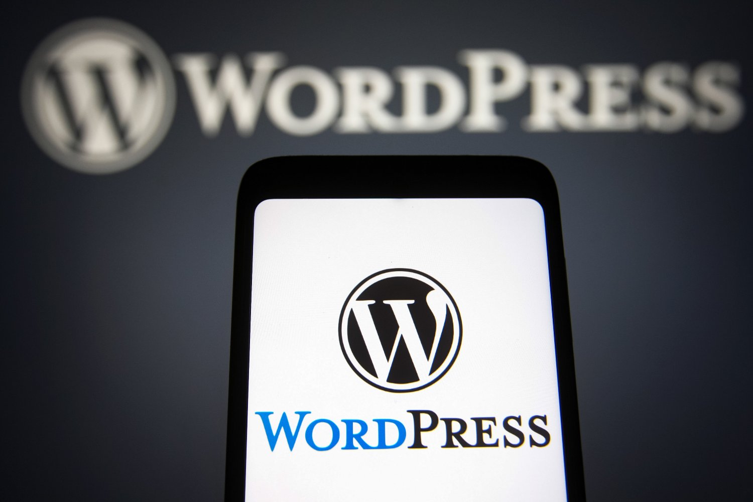 A photo illustration in which the WordPress logos (WP, WordPress.org) are seen on a smartphone and in the background.