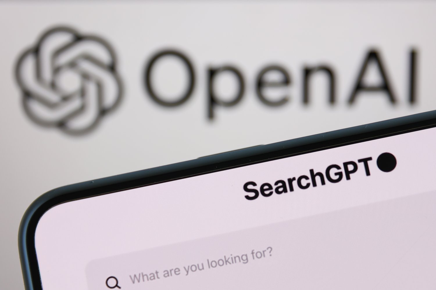 OpenAI logo displayed on a laptop screen and SearchGPT website displayed on a phone screen are seen in this illustration photo