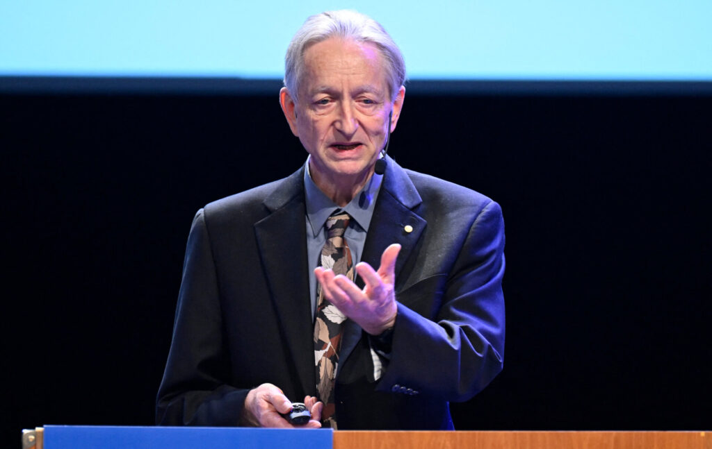 Geoffrey Hinton speaking at a podium.